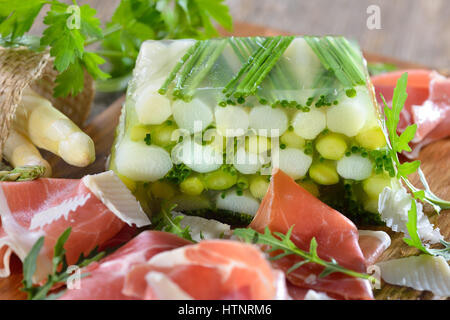 Gelatina di asparagi con carni bianche e verdi Asparagi e erba cipollina, servita con una deliziosa spagnolo il prosciutto Serrano e il parmigiano reggiano Foto Stock