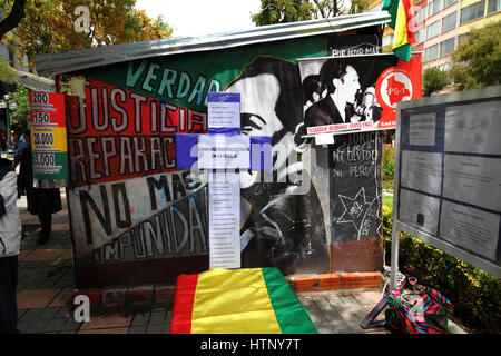 La Paz, Bolivia, 13 marzo 2017. Un murale che mostra Marcelo Quiroga Santa Cruz sul muro del campo istituito dalle vittime delle dittature militari boliviane di fronte all'edificio del Ministero della Giustizia. Oggi le vittime commemorano 5 anni di proteste che chiedono giustizia e risarcimento per coloro che hanno sofferto, e che il governo rilascia fascicoli del periodo per contribuire a stabilire la verità su ciò che è accaduto. La croce ha i nomi di 22 manifestanti / sopravvissuti che sono morti dall'inizio delle proteste. Credit: James Brunker / Alamy Live News Foto Stock