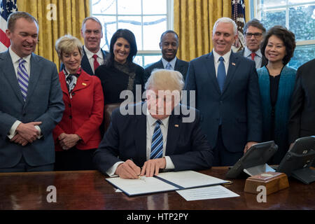 Washington DC, USA, 13 marzo, 2017 Il presidente statunitense Donald Trump J (C) firma un ordine esecutivo intitolata, "Piano globale per riorganizzare il ramo esecutivo', accanto a membri del suo gabinetto all Ufficio Ovale della Casa Bianca di Washington, DC, STATI UNITI D'AMERICA, Foto Stock