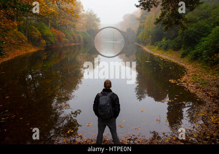 Traveler vicino Rakotzbrücke (Ponte del Diavolo) all inizio di mattina nebbia in autunno Kromlau, Germania Foto Stock