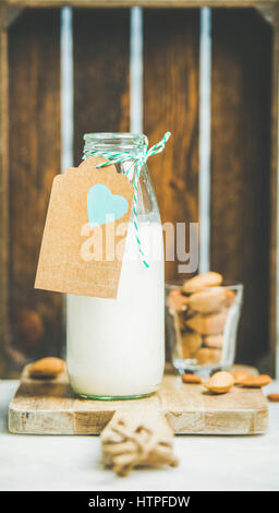 Vegano fresco latte di mandorla libera il latte in bottiglia di vetro con carta craft etichetta con copia spazio, scatola di legno a sfondo. Vegano vegetariano crudo, sano, Foto Stock