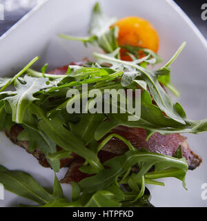 Fetta di prosciutto o jamon con foglie di rucola Foto Stock