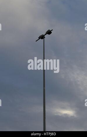 Imponente il palo della luce con silhouette nuvoloso cielo blu in background Foto Stock