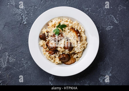 Risotto con funghi porcini che serve dimensioni sulla pietra scura sullo sfondo Foto Stock