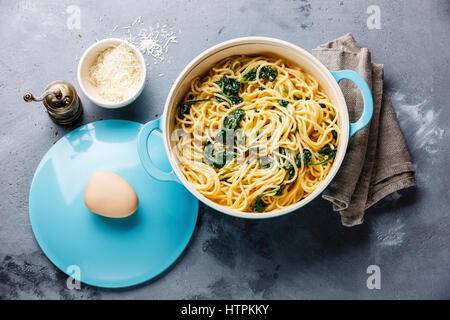 Spaghetti con spinaci e salsa alla panna in padella in grigio sullo sfondo di calcestruzzo Foto Stock