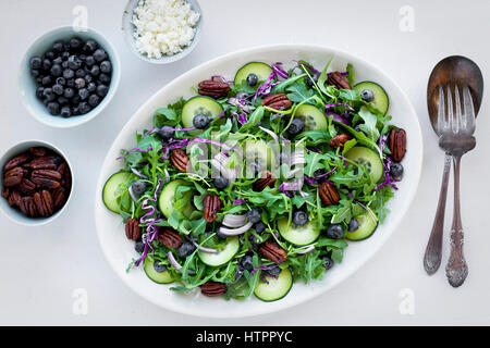 Noci Pecan piccante Feta Insalata di rucola servita con mirtilli, le noci pecan e la feta. Fotografato su uno sfondo bianco. Foto Stock