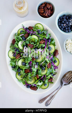 Noci Pecan piccante Feta Insalata di rucola servita con crostini di noce Sherry vinaigrette a base di Feta, i mirtilli, le noci pecan e la feta. Fotografato su uno sfondo bianco. Foto Stock