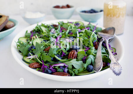 Noci Pecan piccante Feta Insalata di rucola servita con pane e vino rosso. Fotografato su uno sfondo bianco. Foto Stock