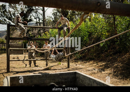 I giovani soldati militari la pratica di arrampicata corda durante la corsa a ostacoli a Bootcamp Foto Stock