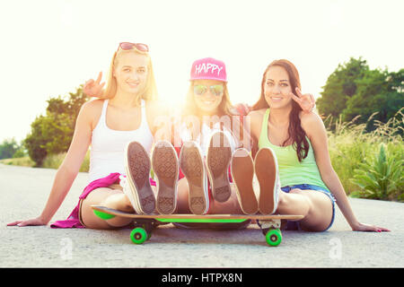 Attraente sorridente hipster teenage amici con lo skateboard, colorised immagine con sun flare Foto Stock