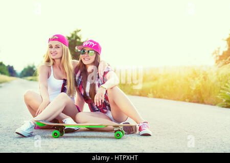 Attraente sorridente hipster teenage amici con lo skateboard, colorised immagine con sun flare Foto Stock