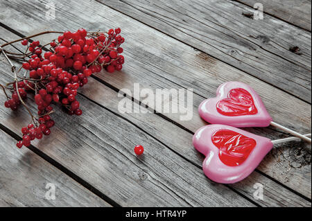 Due cuori dolci su sfondo di legno con frutti di bosco Foto Stock