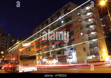 Esterno di un vecchio alloggiamento pubblico in ngau tau Kok, Hong Kong, con il sentiero di luce di un passaggio in autobus Foto Stock