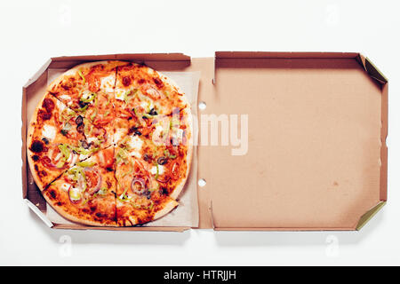Vista dall'alto di una pizza in una casella su un tavolo bianco, close-up Foto Stock