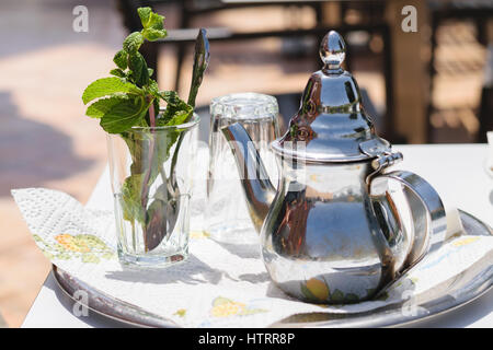 Immagine di una teiera e un vetro con le foglie di menta per preparare un tè alla menta in stile marocchino. Foto Stock