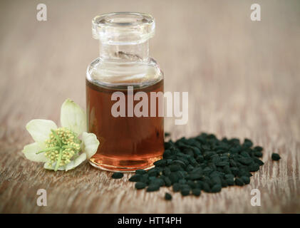 Nigella fiore con semi e olio essenziale in una bottiglia di vetro Foto Stock