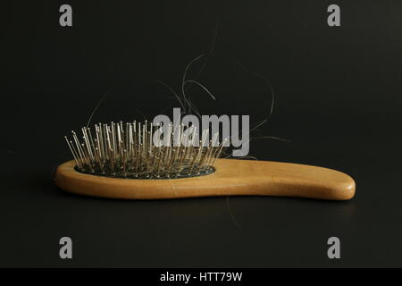 Mazzetto di capelli sulla spazzola per capelli su sfondo nero Foto Stock