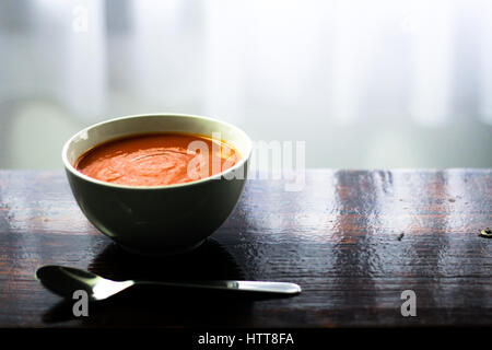 Immagine di un bawl di zuppa di pomodoro con un cucchiaio sul lato seduta su una tavola di legno Foto Stock