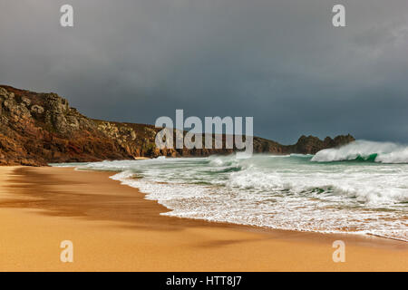 Guardando Logan Rock da Porthcurno Beach. Il 28 febbraio 2017. Dark nuvole temporalesche passando sopra. Con il bel sole d'inverno e una marea. © Foto Stock