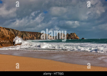 Guardando Logan Rock da Porthcurno Beach. Il 28 febbraio 2017. Dark nuvole temporalesche passando sopra. Con il bel sole d'inverno e una marea. © Foto Stock