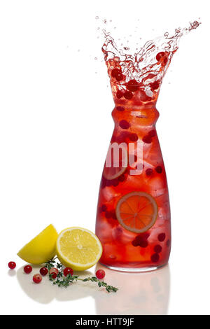 Splash dal cubo di ghiaccio di cadere nella bevanda con mirtillo palustre, limone e timo Foto Stock