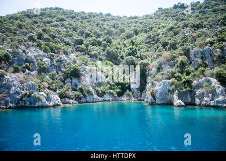 Città Sommersa di Kekova nella baia di Uchagiz vista dal mare in provincia di Antalya della Turchia con il mare turqouise rocce e cespugli greepn Foto Stock