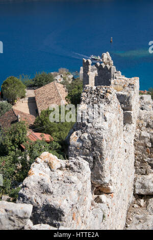 Muro di fortificazione di Simena castello Kalekoy shot sulla giornata soleggiata con parete in shapr focus e alcuni alberi e tetti di casa e mare sfocato Foto Stock