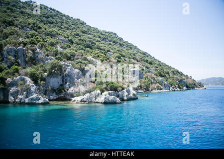 Città Sommersa di kekova nella baia di uchagiz vista dal mare in provincia di Antalya della Turchia con il mare turqouise rocce e cespugli greepn Foto Stock