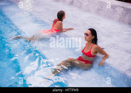 Le giovani donne a rilassarci in piscina Foto Stock