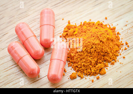 Heap la curcuma in polvere e capsule su texture di legno, asiatica di spezie ed erbe Foto Stock