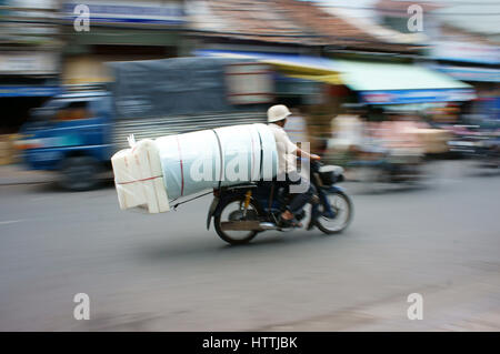 HO CHI MINH, VIET NAM- MAR 30: Unsafe, pericolo di trasporto su strada vietnamita, uomo ride moto, trasporto merci in sovraccarico, voluminoso, Foto Stock