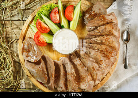 Chiudere l'immagine orizzontale di varie carni sulla scheda servente con prosciutto, carne di maiale, carne di manzo, il prezzemolo e olive su legno rustico. Focus sulla parte laterale di servire bo Foto Stock