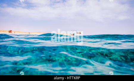 Mar Rosso superficie a Marsa Alam, Fisher barca e il deserto in background Foto Stock