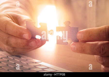 Primo piano delle mani dell'uomo tenendo i pezzi del puzzle Foto Stock