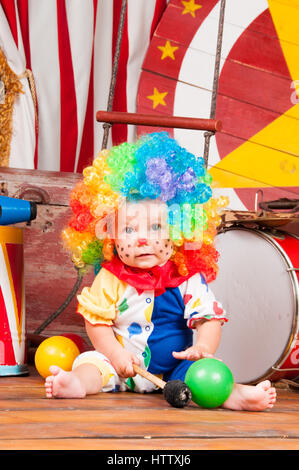 Little baby clown con naso rosso multicolore in parrucca con sfere Foto Stock