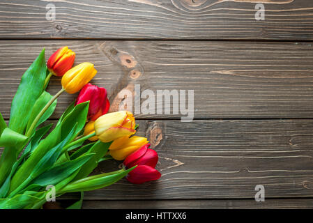 Bouquet di tulipani in una carta shopping bag su uno sfondo di legno, concetto di sconti e vendite su la Giornata della donna o della mamma o di Pasqua Foto Stock