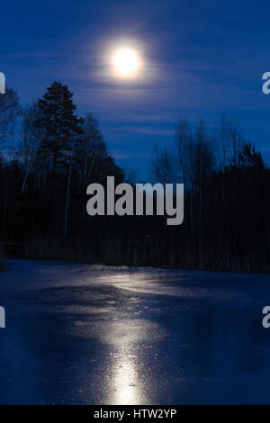 La luna e il lago di ghiaccio in Svezia Scandinavia Europa. Bellissimo paesaggio e natura foto di notte. Graziosa tonalità blu. Serata a freddo con acqua congelata Foto Stock