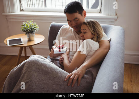 L uomo dando regalo a sorpresa per la sua donna sul divano Foto Stock