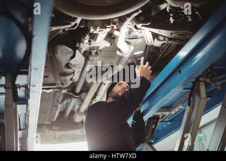 Mechanic esaminando un auto con la torcia elettrica Foto Stock