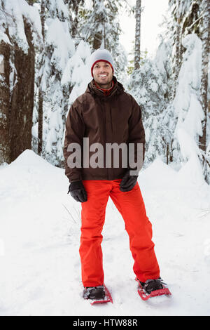 Sciatore sorridente in piedi su paesaggi innevati Foto Stock