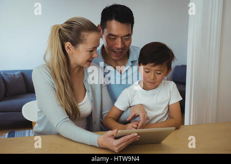 La famiglia tramite tavoletta digitale in salotto Foto Stock