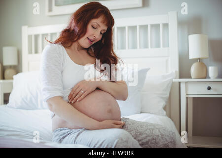 Premurosa donna incinta rilassante sul letto Foto Stock