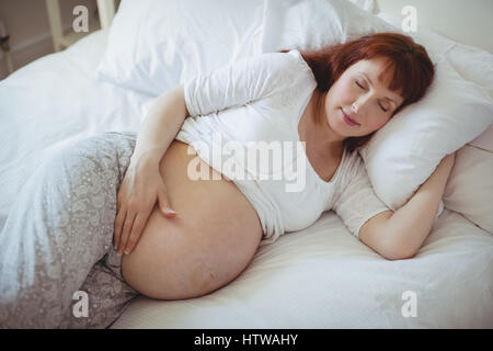 Donna incinta di dormire sul letto Foto Stock