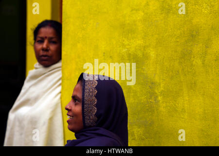 Una donna indiana di fronte ad una parete di colore giallo e un altro in background, Khajuraho, India Foto Stock