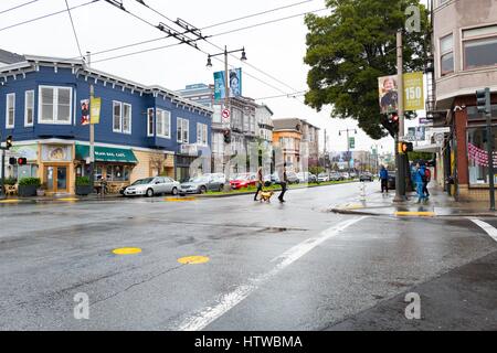 In un giorno di pioggia nel nord di Panhandle (NoPA) quartiere di San Francisco, California, persone attraversano in corrispondenza dell'intersezione di Divisadero Street e Hayes Street, 19 febbraio 2017. Foto Stock