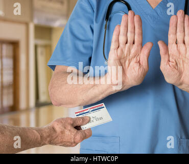 Senior medico in scrubs rifiutando Tessera Medicare Foto Stock