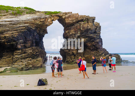 Gruppo di turisti da un arco in pietra presso la spiaggia delle cattedrali monumento naturale a ribadeo comune, provincia di Lugo, Galizia, Spagna, Europa Foto Stock