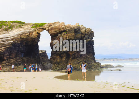 I turisti da un arco in pietra presso la spiaggia delle cattedrali monumento naturale a ribadeo comune, provincia di Lugo, Galizia, Spagna, Europa Foto Stock