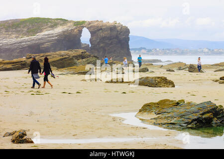 I turisti da un arco in pietra presso la spiaggia delle cattedrali monumento naturale a ribadeo comune, provincia di Lugo, Galizia, Spagna, Europa Foto Stock