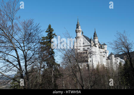 Castello con alberi circostanti contro il cielo blu - Castello di Neuschwanstein Foto Stock